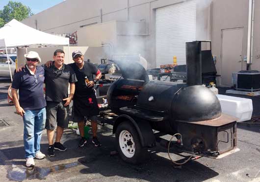 Craig Danto (center) checks in with the Danto Builders team of competitors—Todd Danto (left) and Keith Samuels—at the Big Bad BBQ. All combined, the teams cooked up 1,800 pieces of barbecued chicken and 5,400 ribs for the 2017 event.